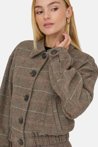 Veste brune de ONLY®, avec un motif à carreaux et une fermeture à boutons, portée par un modèle blond.