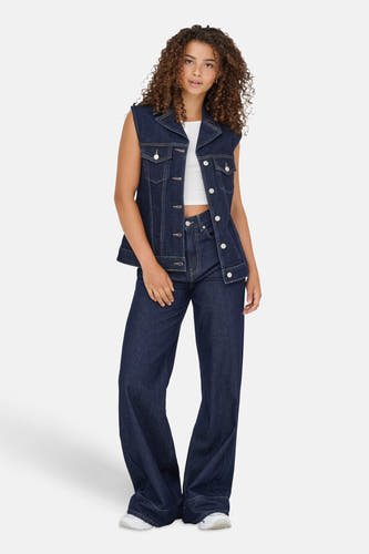 Veste en denim bleu marine de ONLY, avec des boutons argentés, portée sur un haut blanc et des jeans bleu marine larges.