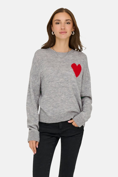 Sweat-shirt gris à col rond de JDY, avec un détail de cœur rouge et porté avec un jean noir et des bijoux argentés.
