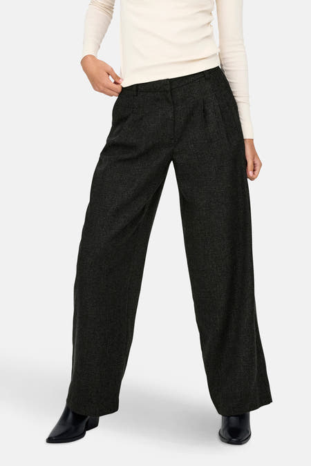 Pantalon gris de JDY, avec des jambes larges et des poches, porté avec un haut blanc et des bottines noires.