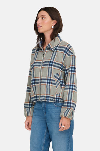 Manteau court multicolore d'ONLY, avec un motif de carreaux et associé à des jeans bleus et des bottes brunes.