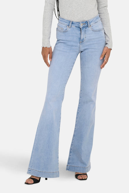 Jean flare bleu clair ONLY, avec une chemise grise et des sandales noires.