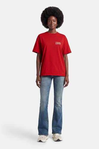 Rood T-shirt met korte mouwen van ONLY®, met "CHERRY LOVE" in wit gedrukt, gecombineerd met blauwe jeans en sneakers.