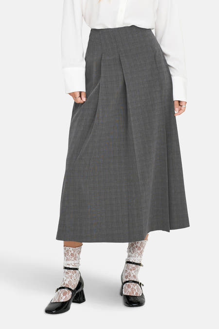 Jupe grise ONLY, avec des plis et un motif rayé, associée à des chaussettes blanches à bords blancs et des chaussures Mary Jane noires.