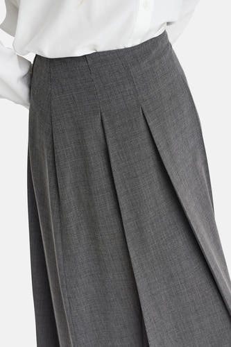 Jupe grise ONLY, avec motif tartan et plis, associée à une blouse blanche.