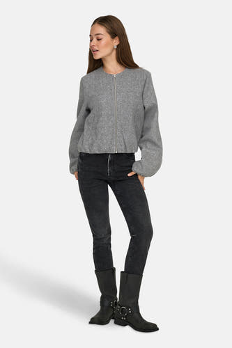 Manteau court gris de JDY, avec des manches longues et une fermeture éclair argentée, associé à un jean noir et des bottes.