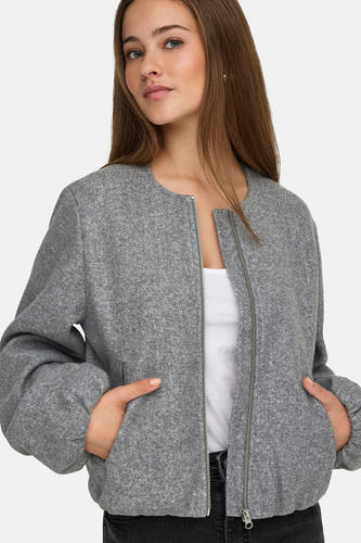 Manteau gris JDY, avec longues manches et fermeture éclair, porté sur un haut blanc.