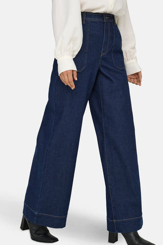 Jean décontracté de denim bleu foncé JDY, avec une taille haute et associé à une blouse blanche.