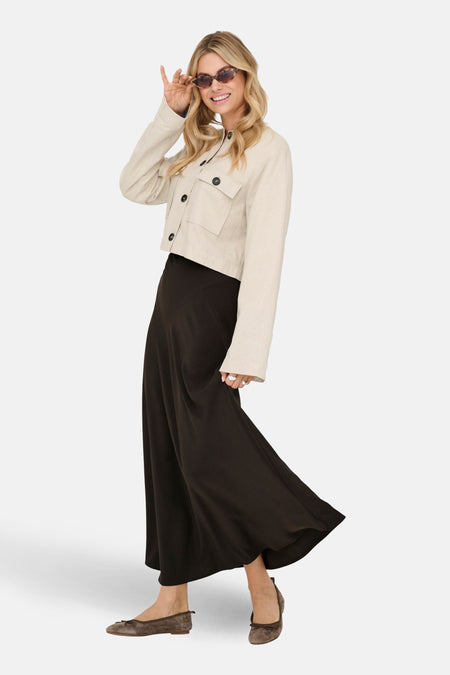 Lange bruine rok van JDY, gedragen met een beige jack en bruine ballerina's.