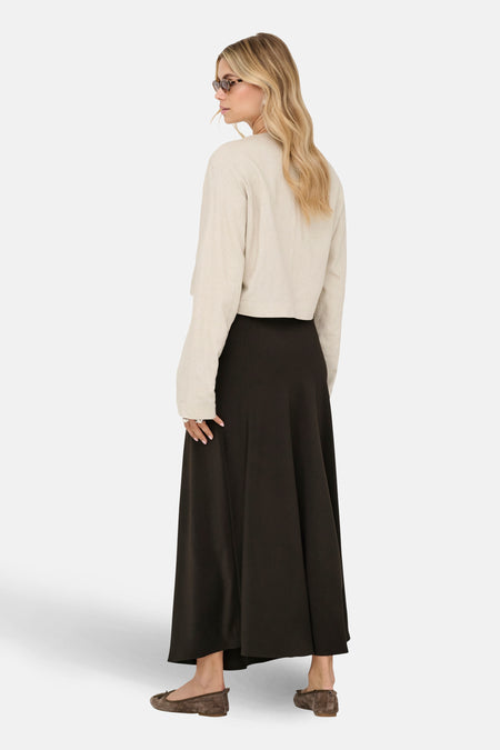 Lange bruine rok van JDY, gezien van achteren, gecombineerd met een beige shirt en bruine ballerina's.
