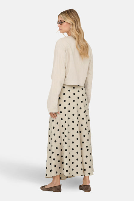 Lange ecru rok van JDY, met een stippenpatroon en gecombineerd met een beige trui en bruine ballerina's.
