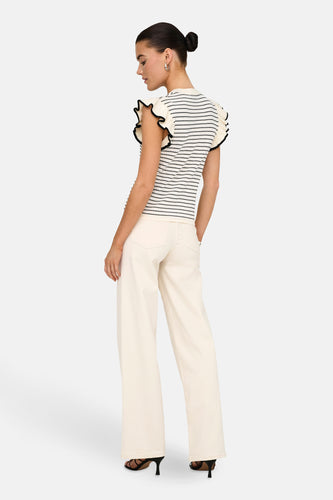 T-shirt blanc de JDY avec des rayures noires et des fronces sur les épaules, associé à un pantalon écru et des talons noirs.