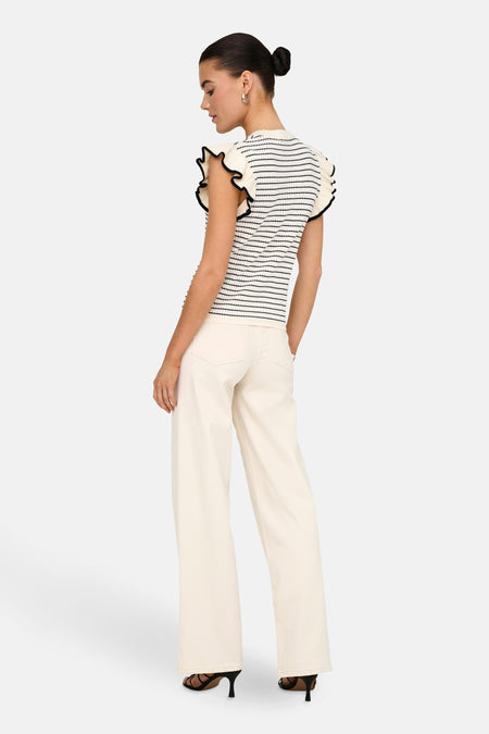 T-shirt blanc de JDY avec des rayures noires et des fronces sur les épaules, associé à un pantalon écru et des talons noirs.