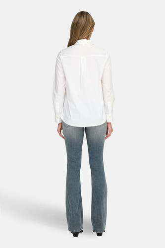 Chemise blanche à manches longues d'ONLY, vue de dos, associée à des jeans bleus.