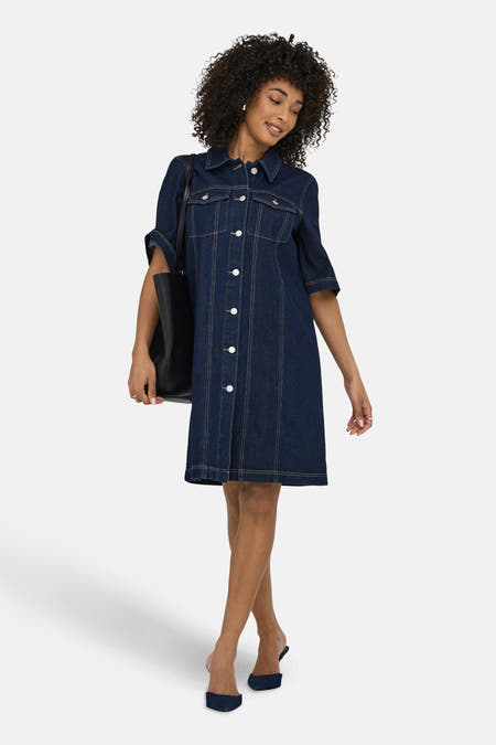 Jupe en denim bleu marine à manches courtes de JDY, avec des boutons blancs et un sac à main noir.