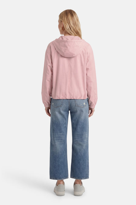 Veste courte rose ONLY® avec capuchon, longues manches, associée à des jeans bleus et des baskets grises, vue arrière.
