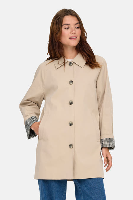 Manteau long beige ONLY avec fermeture à boutons, associé à des jeans larges et des bottines grossières.