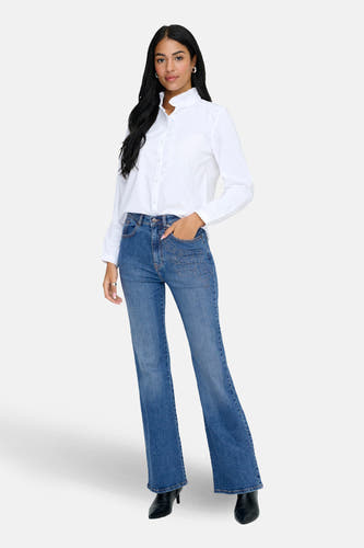 Middenblauwe denim flared jeans van ONLY met geborduurde details op de zakken, gecombineerd met een wit overhemd.
