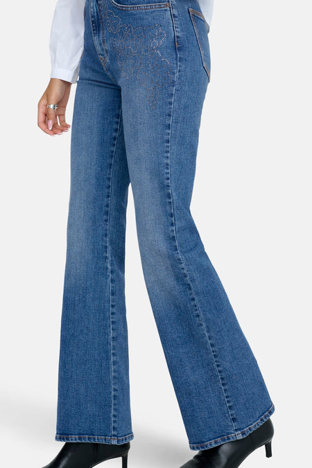 Jean flare bleu moyen d'ONLY, avec des détails strass sur les poches et des escarpins noirs.