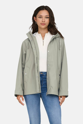 Kaki de pluie ONLY, avec un capuchon, portés avec une chemise blanche et des jeans bleus.