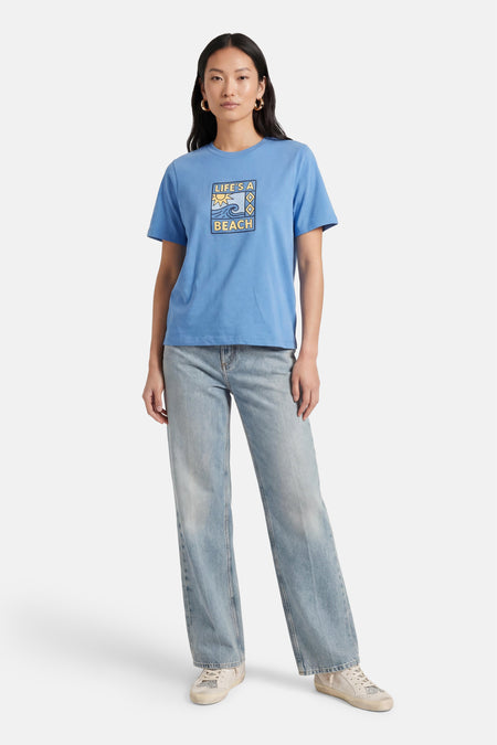 Blauw T-shirt met korte mouwen van ONLY®, met een "Life's a Beach" print, gecombineerd met jeans en sneakers.
