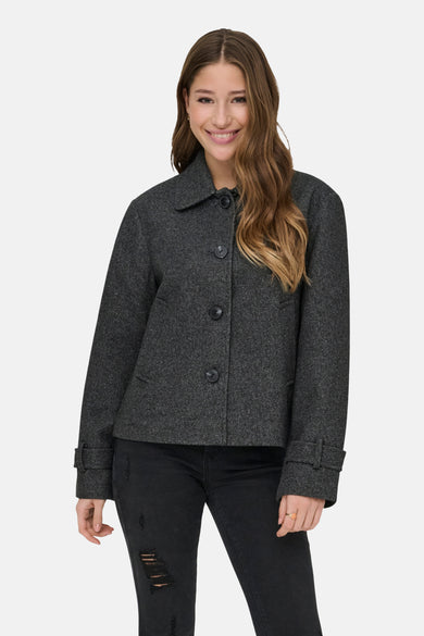 Manteau court gris d'ONLY, avec fermeture à boutons, porté avec un pantalon noir et des bottes noires.