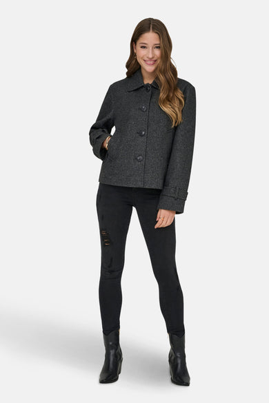 Grijze korte jas van ONLY, met knoopsluiting, gedragen met zwarte broek en zwarte laarzen.
