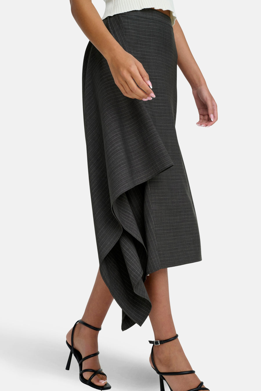 Donkergrijze gestreepte rok met asymmetrische zoom en zwarte hakken.