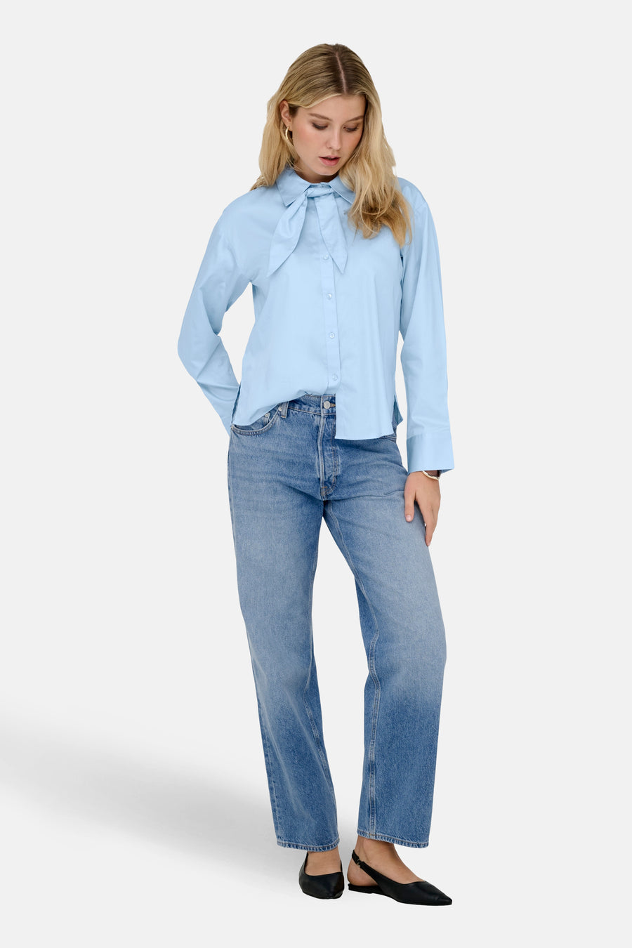Chemise bleue à manches longues de JDY, avec un détail de nœud et associée à un jean et des chaussures noires.