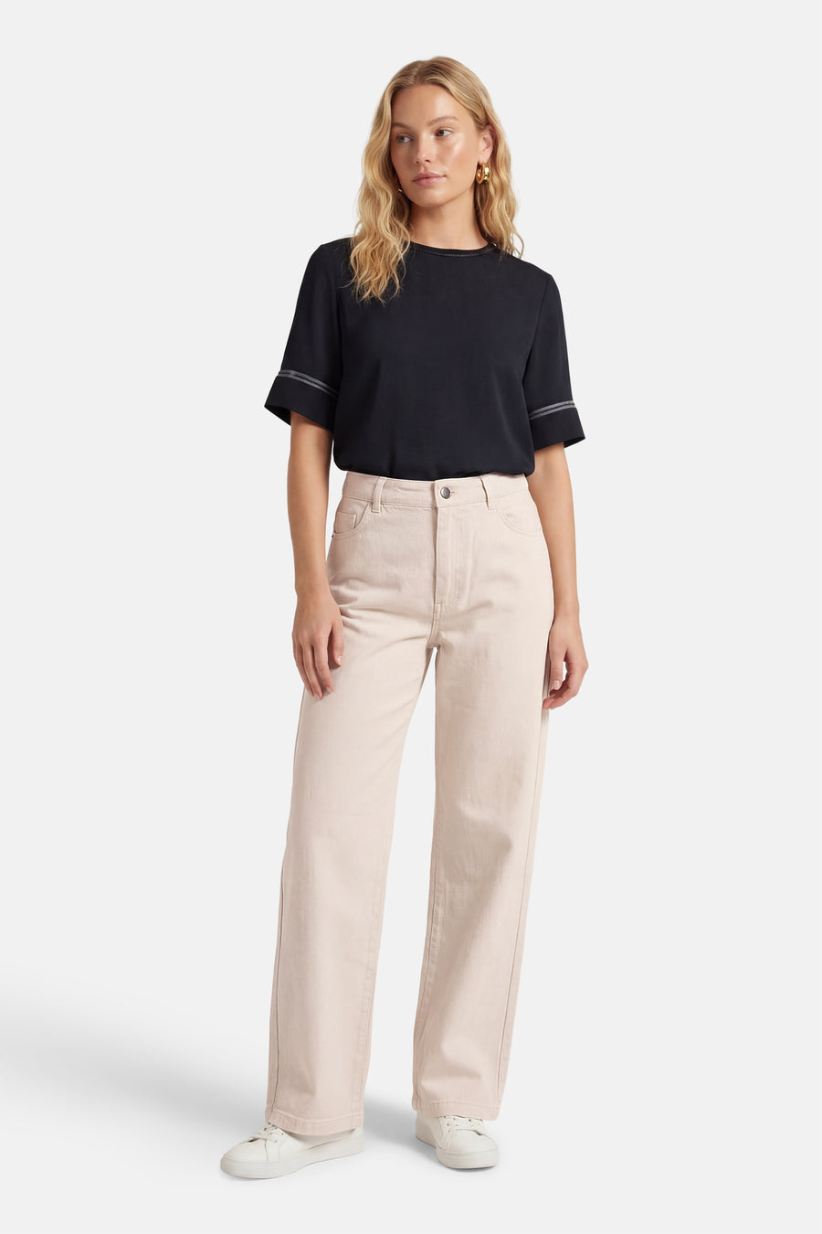 Jean de couleur beige de JDY, avec jambes larges et coutures apparentes, porté avec un t-shirt noir et des baskets blanches.