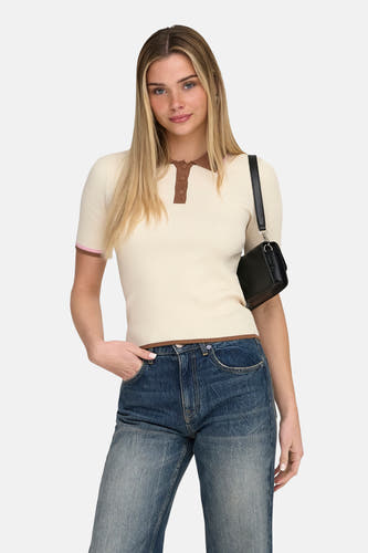 Ecru polo met korte mouwen van ONLY, met bruine details en gedragen met een jeans.
