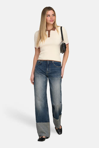 Ecru polo met korte mouwen van ONLY, met bruine randen en gedragen met wijde jeans en zwarte schoenen.
