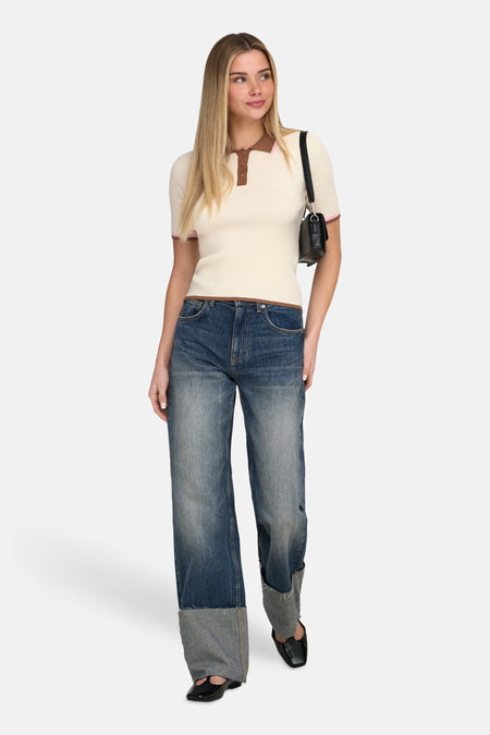 Ecru polo met korte mouwen van ONLY, met bruine randen en gedragen met wijde jeans en zwarte schoenen.
