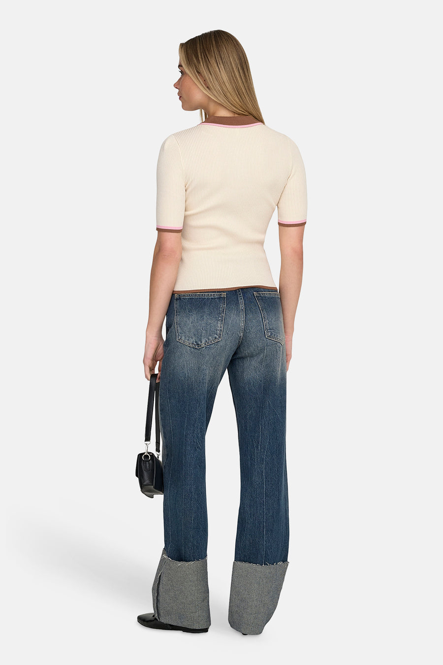 Ecru polo met korte mouwen van ONLY, met bruine en roze accenten, gecombineerd met jeans en een zwarte handtas.
