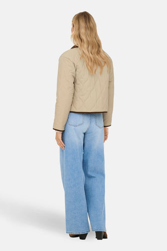 Beige korte jas van JDY, met bruine randen en lange blauwe jeans.
