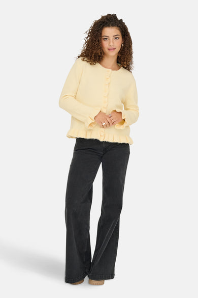 Cardigan jaune d'ONLY, avec des smocks au bas et des manches, porté avec un jean noir.