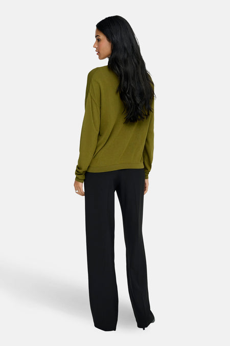 Groene trui met V-hals van JDY, met lange mouwen en gecombineerd met een zwarte pantalon.
