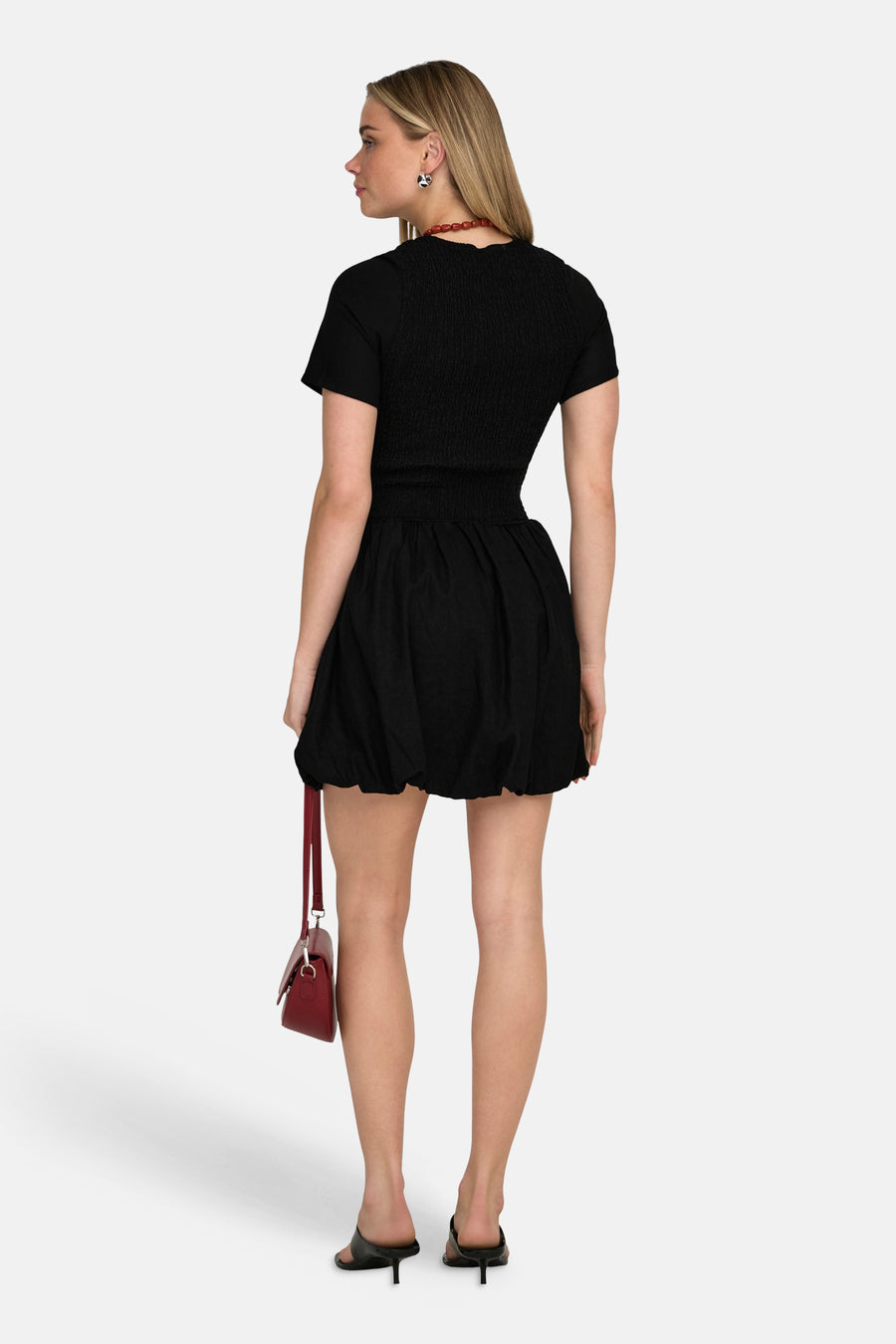 Robe noire à manches courtes de ONLY, avec un haut smocké et un sac rouge.