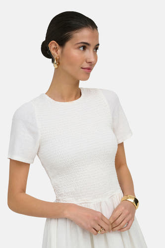 Robe blanche à manches courtes ONLY®, avec un corsage smocké et une jupe fluide, portée par un mannequin.