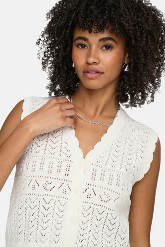 Gilet blanc ONLY® à motif ajour crocheté, col en V festonné et fermeture à boutons, porté par un mannequin avec chaîne argentée.