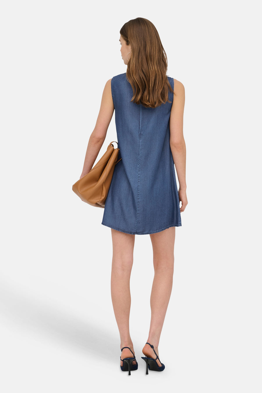Robe sans manches en denim bleu foncé de ONLY® coupe trapèze, vue de dos, avec un sac marron et des escarpins slingback noirs.