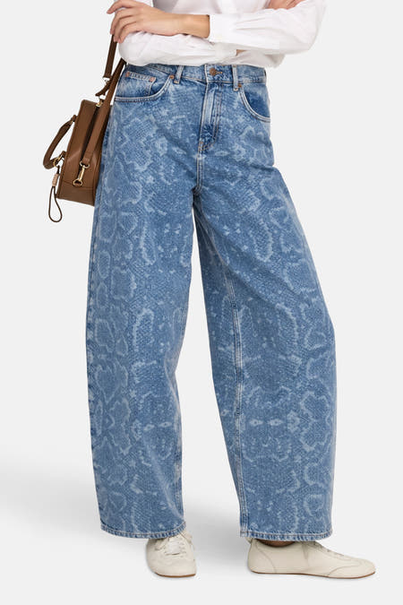 Jean bleu marine de ONLY, avec une légère imprimé combininés avec une blouse blanche et une poche main marron.