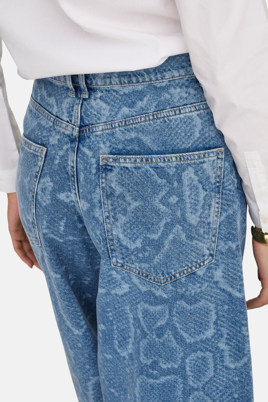 Blauwe denim broek met print en wit overhemd.
