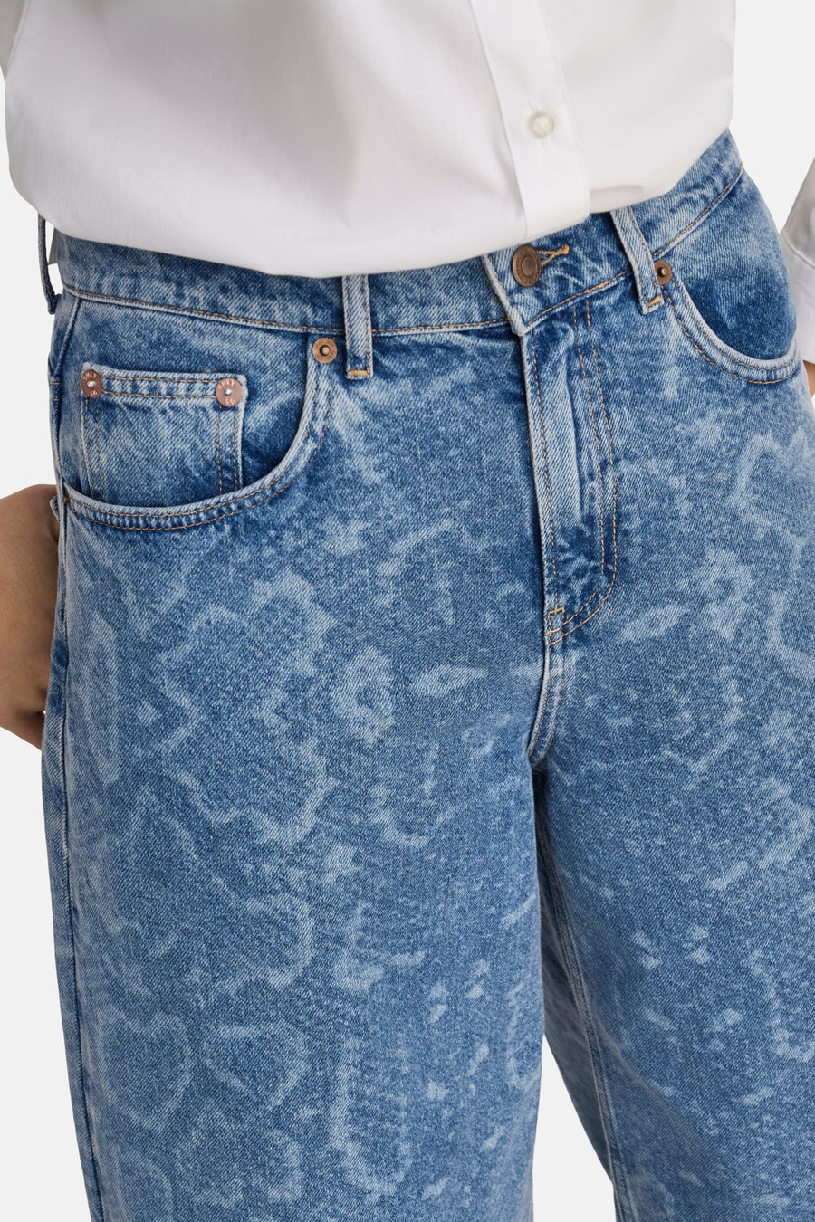 Close-up van een persoon in blauwe jeans en een wit overhemd.