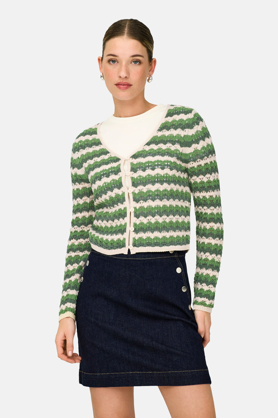Cardigan vert de ONLY, avec des rayures de couleur crème et porté sur une chemise blanche et une jupe bleu foncé.