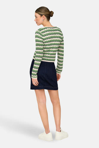Gilet vert de ONLY® avec un motif zigzag rayé, combiné avec une jupe bleu foncé et des baskets blanches.