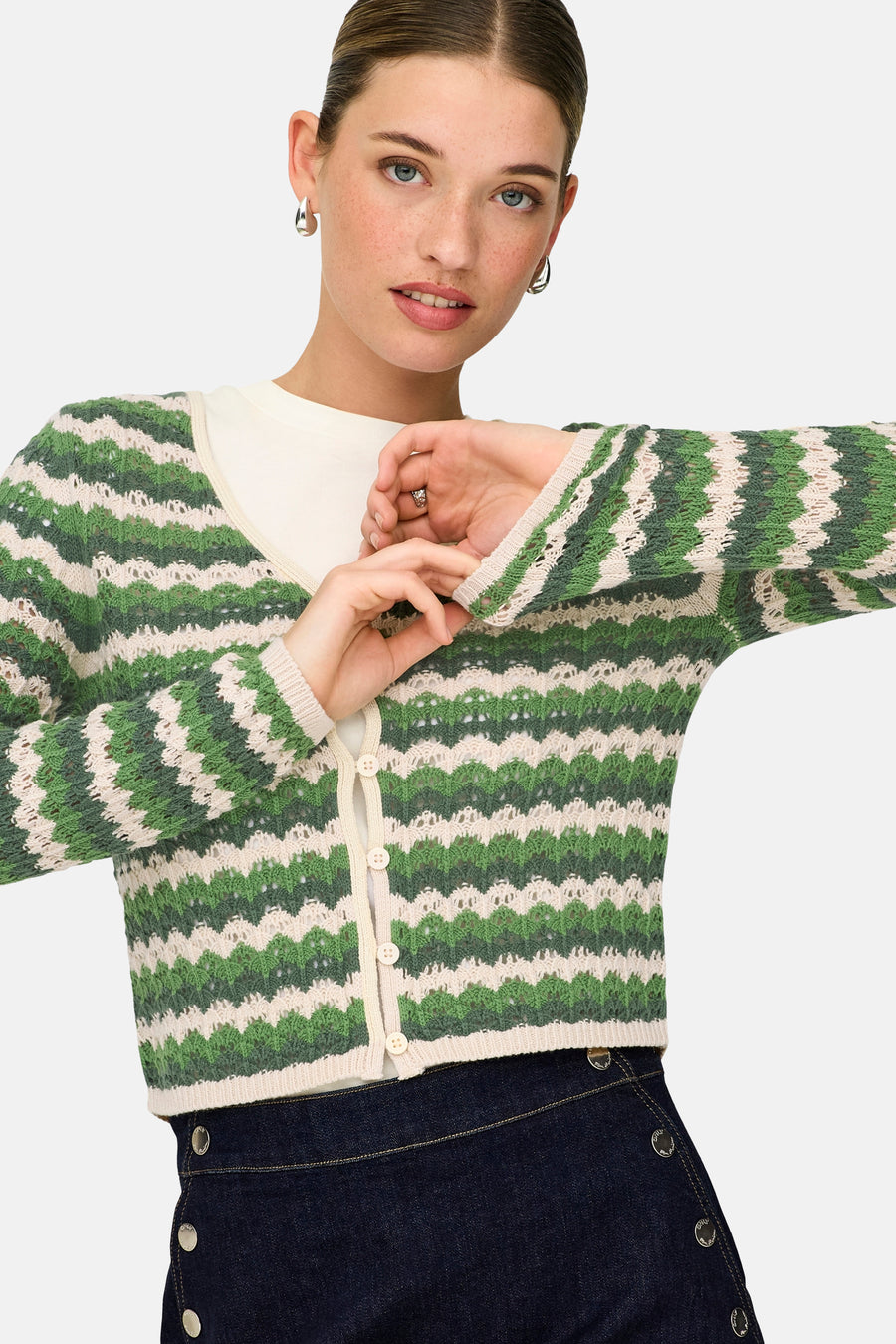 Gilet vert de ONLY, avec motif rayé et fermeture à boutons, porté sur une chemise blanche et une jupe bleu foncé à boutons.