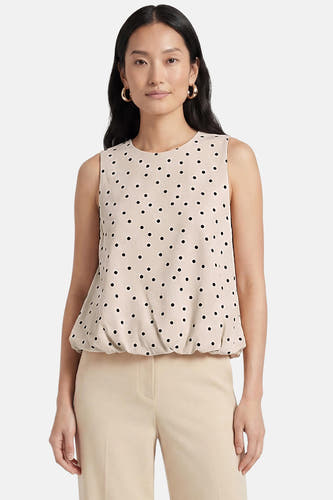 Ecru mouwloze top van ONLY® met zwarte stippen en elastische zoom, gedragen met een lichte broek.