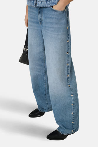 Jean droit bleu clair GIANNA d'ONLY, avec boutons argentés sur le côté et un sac à main noir.