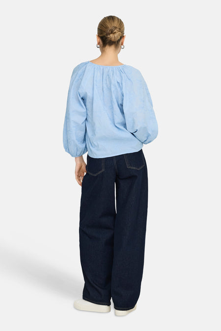 Chemisier bleu à manches longues de ONLY, avec détails brodés, associé à un jean bleu foncé et des baskets blanches.